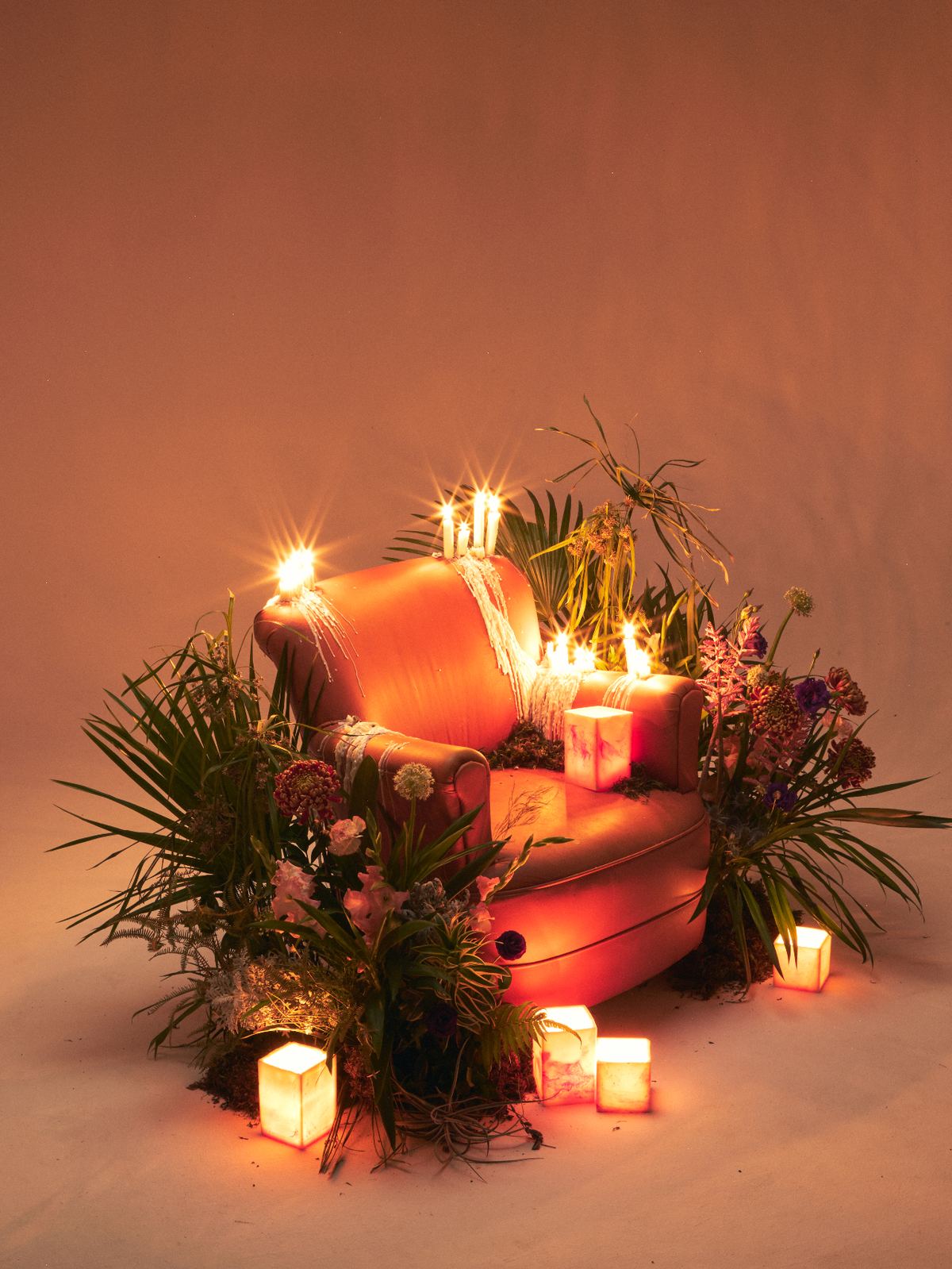 Detalhe cenográfico — cravos, orquídeas e velas sobre musgo