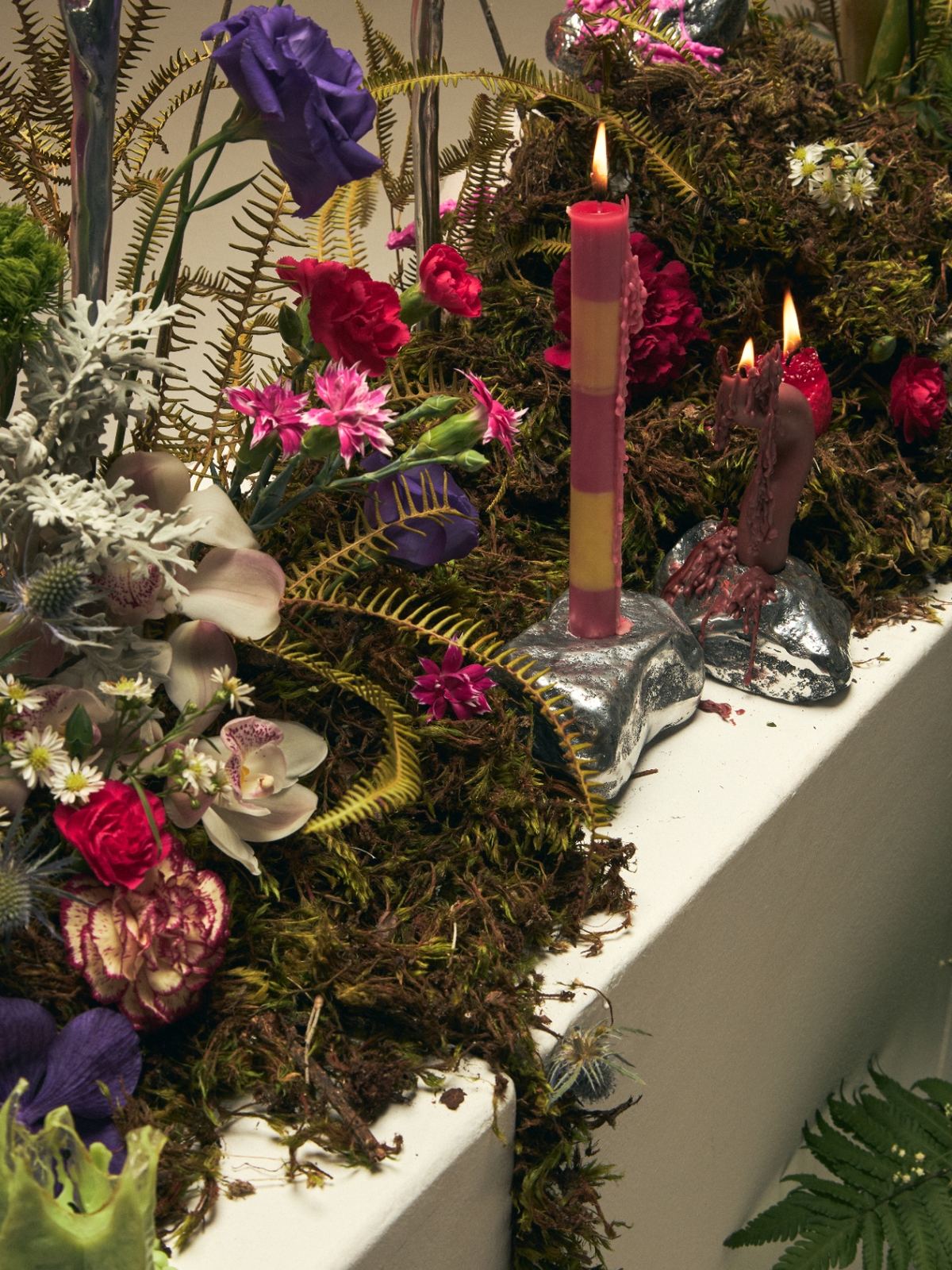 Cenografia autoral — instalação escultórica com flores coloridas e velas